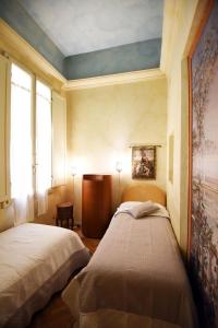 フィレンツェにあるItalian Experience-Suite Medici Loft 8の壁に絵画が飾られた部屋のベッド2台