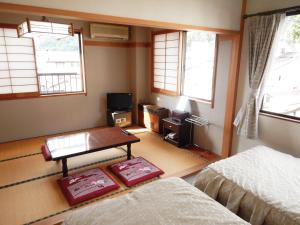 a room with two beds and a table and windows at Togoro in Nozawa Onsen