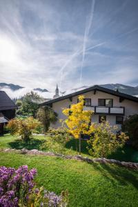 a white house with a yellow tree in the yard at Appartementhaus Winter in Radstadt