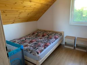 małe łóżko w pokoju z drewnianym sufitem w obiekcie Ostoja Wilka w mieście Grochowce