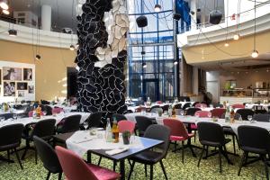 una sala da pranzo con tavoli, sedie e una grande parete di Holiday Inn Stuttgart, an IHG Hotel a Stoccarda