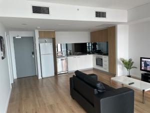 ein Wohnzimmer mit einem schwarzen Sofa und einer Küche in der Unterkunft RNR on Franklin in Adelaide