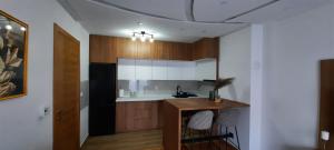 une cuisine avec des placards en bois et un comptoir avec des tabourets dans l'établissement Apartman Orl Lux, à Lukavica