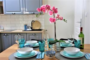 une table avec des plats bleus et un vase avec des fleurs roses dans l'établissement Apartamenty Royal Maris 6 - najlepsza lokalizacja w Ustce, blisko plaży i portu, bezpłatny parking, ścicsłe centrum, à Ustka