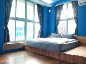 een slaapkamer met blauwe muren en een bed met ramen bij Tainan MacArthur Homestay in Tainan