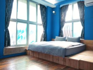a bedroom with blue walls and a bed with windows at Tainan MacArthur Homestay in Tainan