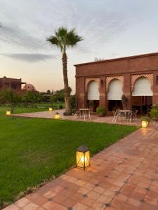 a light in the grass with a palm tree and a building at LES JARDINS DE MARRAKECH in Marrakesh