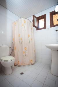 a bathroom with a toilet and a shower curtain with flowers at SINI Apartments 3 in Kefalos