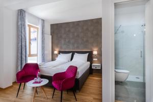 a hotel room with a bed and two pink chairs at Hotel Dvorec in Tolmin