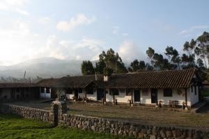 un groupe de bâtiments avec des montagnes en arrière-plan dans l'établissement Hacienda La Merced Baja, à Hacienda Zuleta