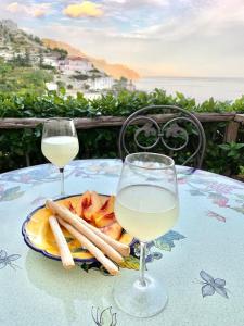 een tafel met een bord eten en twee glazen wijn bij Mariuccia House in Amalfi