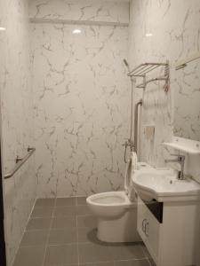 a white bathroom with a toilet and a sink at AB Star Suites in General Santos