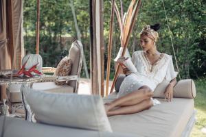 a woman sitting on a swing reading a book at Khwan Beach Resort - Luxury Glamping and Pool Villas Samui - Adults Only - SHA Extra Plus in Mae Nam