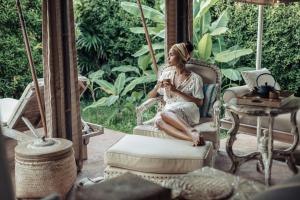 a woman sitting in a chair on a porch at Khwan Beach Resort - Luxury Glamping and Pool Villas Samui - Adults Only - SHA Extra Plus in Mae Nam