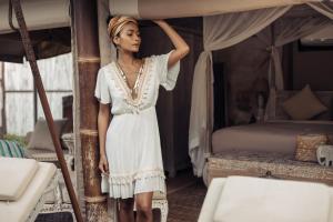 a woman in a white dress standing next to a bed at Khwan Beach Resort - Luxury Glamping and Pool Villas Samui - Adults Only - SHA Extra Plus in Mae Nam
