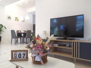 Merdeka One Homestay 8pax 4Rooms في سيبو: غرفة معيشة فيها تلفزيون وطاولة فيها ورد