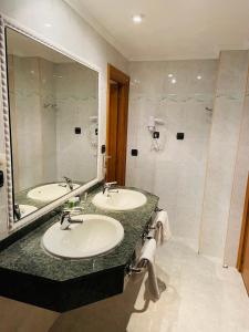 a bathroom with two sinks and a large mirror at Sercotel Rey Sancho in Palencia