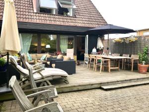 una terraza de madera con sillas, mesas y sombrilla en Rivera Hill, en Båstad