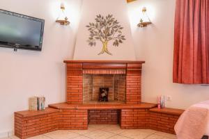 a living room with a brick fireplace with a tv at VILLA MITZELOS in Skiathos