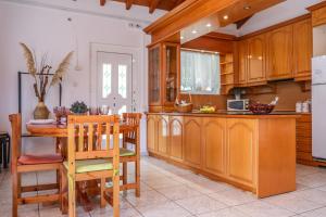 - une cuisine avec des placards en bois, une table et des chaises dans l'établissement VILLA MITZELOS, à Skiathos Chora