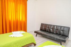 a room with a bed and a leather couch at VILLA MITZELOS in Skiathos