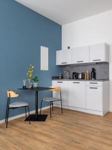 cocina con armarios blancos, mesa y sillas en limehome Augsburg Annastraße, en Augsburg