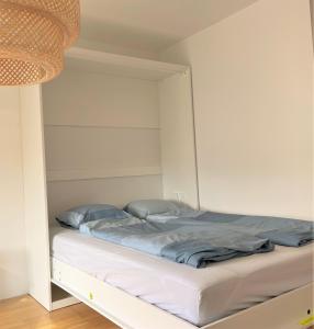 ein Bett in einem Schlafzimmer mit einer weißen Wand in der Unterkunft Holiday Suites Sankt Martin in Klagenfurt am Wörthersee