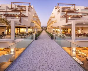 a walkway between two buildings with tables and chairs at Tabaiba Princess in Maspalomas