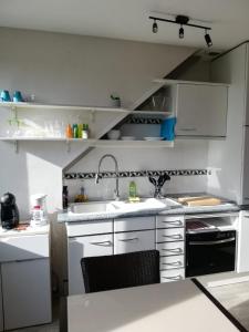 una cocina con armarios blancos y fregadero en Studio, 15mn de la mer 5mn de la rue de la mer avec jouissance du jardin et parking en Cabourg