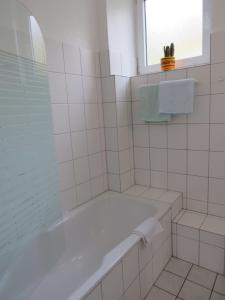 a white bathroom with a tub and a window at Residenzpark Willingen Typ C in Willingen