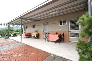 a patio with tables and chairs on a house at Ganoun Homestay in Meinong