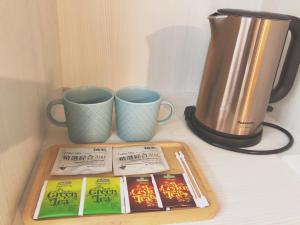 a table with two coffee mugs and a tray with books at SUN 9 Inn in Hengchun South Gate