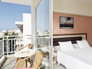 Schlafzimmer mit einem Bett und einem Tisch auf dem Balkon in der Unterkunft Pearl Hotel in Rhodos (Stadt)