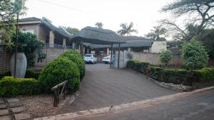 a house with a car parked in front of a driveway at Forest hills lodge in Louis Trichardt