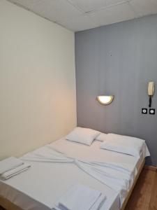 a white room with a bed with white sheets at Hôtel Le Milan in Lourdes +17 photos