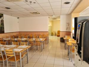 une salle à manger avec des tables, des chaises et un tableau blanc dans l'établissement Hôtel Le Milan, à Lourdes