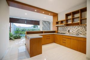 a kitchen with wooden cabinets and a large window at Vasudha Hostel Canggu in Canggu