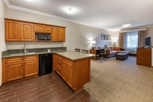 a kitchen with wooden cabinets and a living room at Comfort Suites Near Six Flags Magic Mountain in Stevenson Ranch