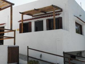 a white building with a balcony with a wooden roof at Aeolos Hotel Apartments in Gythio