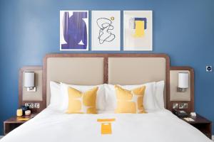 
a bedroom with a bed, a lamp, and a painting on the wall at voco Grand Central - Glasgow, an IHG Hotel in Glasgow
