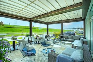 a conservatory with patio with couches and tables and chairs at Hotel Regina Maris in Norddeich