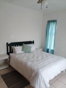 a bedroom with a large white bed with a blue curtain at Spacious 1bed + braai 13km to Paternoster beach in Vredenburg