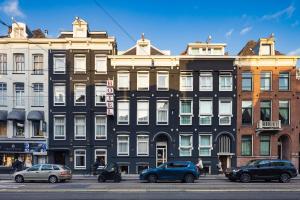 een groep gebouwen in een stadsstraat met geparkeerde auto's bij Huygens Place Amsterdam in Amsterdam