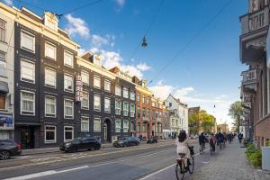 una mujer montando una bicicleta por una calle con edificios en Huygens Place Amsterdam en Ámsterdam