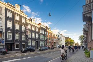 una mujer montando una bicicleta por una calle con edificios en Huygens Place Amsterdam, en Ámsterdam
