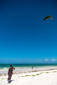 un hombre volando una cometa en la playa en Hakuna Majiwe Beach Lodge en Paje