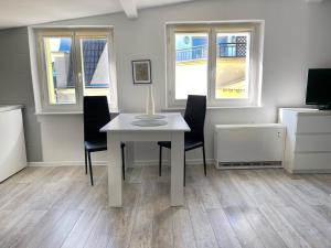 a white table and chairs in a room with windows at Apartament Dotyk - Monte Cassino- Kameralne Poddasze in Sopot