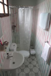 a bathroom with a white toilet and a sink at Micaval Residential in São Tomé