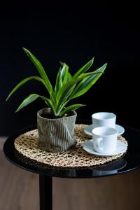a potted plant sitting on a table with two cups at Metro Młynów Warsaw Wola Apartment Długosza by Renters in Warsaw