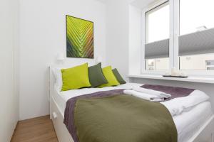 a bedroom with a bed with yellow and green pillows at Metro Młynów Warsaw Wola Apartment Długosza by Renters in Warsaw